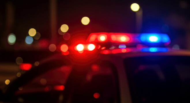 Closeup of blurred police sirens lights flashing at night in urban setting.