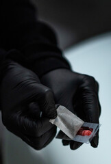 Gloved hands open a package containing a disposable needle