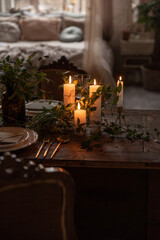 Burning candles on wooden table with plant