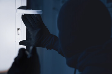 Break-In Concept. Back view of unrecognizable criminal in black balaclava entering victim's house,...