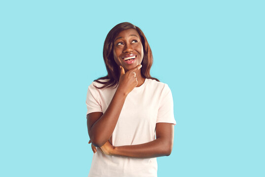 Close up portrait of young african american woman looking to the side thoughtfully and keeping her mouth open isolated on studio blue background. Sale, advertising and people emotions concept.