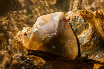 Pinkish-brown chipped flint lying in a stream
