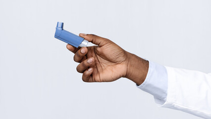 Close up of asthma inhaler holding by african american doctor, white studio background
