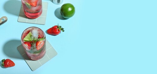 Glasses of delicious strawberry mojito on light blue background with space for text