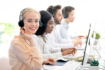 Team of diverse hotline operators with headphones providing service to clients at call center....