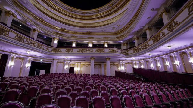 Lavish theatre interior revealing plush purple velvet seats, softly glowing with warm illumination, capturing elegant anticipation before theatrical performance