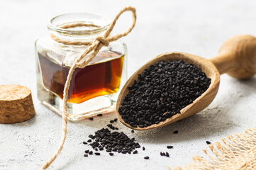 Glass bottle of black cumin seeds essential oil , Nigella Sativa in spoon on rustic background. Organic herbal medicine for many diseases, black cumin