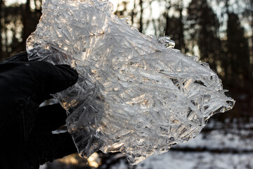 A shard of ice, with a captivating pattern, against the backdrop of the winter sun