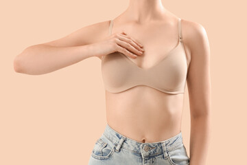 Young woman in bra on beige background