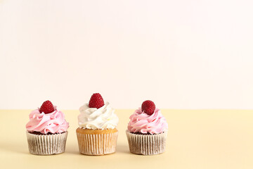 Tasty raspberry cupcakes on beige background
