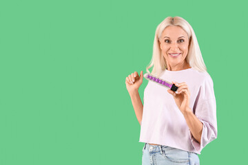 Mature woman with vibrator on green background