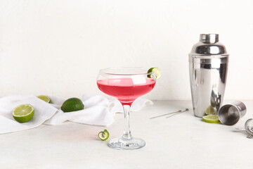 Glass of Cosmopolitan cocktail with lime on white background