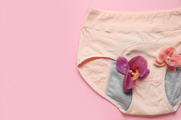 Composition with period panties and beautiful flowers on pink background