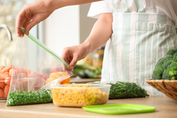 Woman holding plastic bag with green peas for freezing in kitchen, closeup