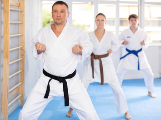 Three athletes have taken starting position and studying and repeating sequence of punches and...