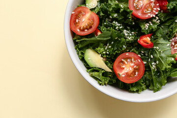 Bowl of tasty kale salad with avocado and tomatoes on color background