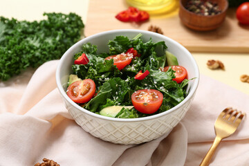 Bowl of tasty kale salad with vegetables, sesame seeds and napkin on color background