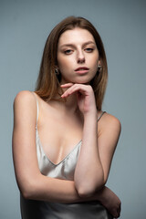 Naklejka premium Elegant woman in a silver satin dress posing stylishly. Accessories include sunglasses and a plaid blazer. Modern, sophisticated, and minimalistic fashion. Neutral background enhances the chic aesthet