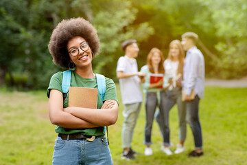 Student Life. Outdoor portrait of smiling black girl posing in front her college friends at campus