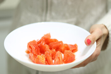 Healthy food. Woman with a plate of cut natural tomato.