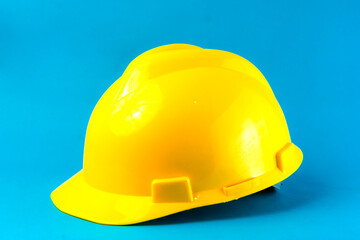 A bright yellow construction hard hat on a blue background. Safety helmet for industrial workers, engineers, and builders, symbolizing workplace protection and occupational safety.