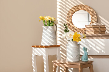 Vases with flowers on stools in room decorated for Easter