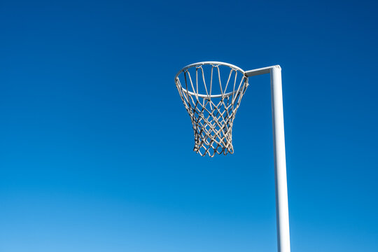 a netball hoop with a white metal pole against a clear blue sky background. A minimalist sports composition of the sports equipment. It is one of a few sports created exclusively for women and girls.