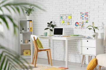 Interior of designer's office with workplace and shelf unit