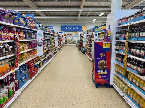Bordon, UK - January 25, 2025: A grocery aisle stocked with food and drink in a Tesco superstore. 