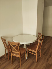 Round white table with four wooden chairs in a corner
