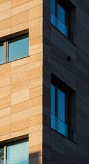 Modern urban architecture with sunlit stone facade and glass windows at dusk