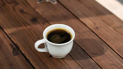 a white coffee cup filled with black coffee on a dark wooden table