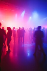 Blurry silhouettes of people dancing in a nightclub with colorful lighting.