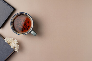 Books with flowers and cup of tea on beige background from above. Flat lay, top view. Copy space