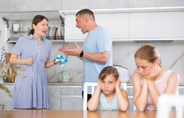 Fototapeta premium Family problem, conflict and people concept - sad children sitting at the table their parents quarreling at home