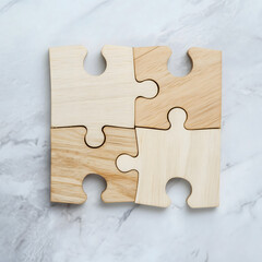 A close-up shot of four interlocking wooden puzzle pieces placed on a white marble background