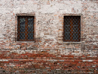 Weathered brick wall with two barred windows
