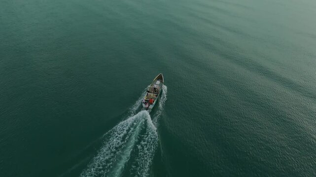 Aerial cinematographic view from a drone along the coast of Rio Hato with a boat sailing towards the sunset, on Farallon beach in the Panamanian Pacific from Panama, 4K vertical video.