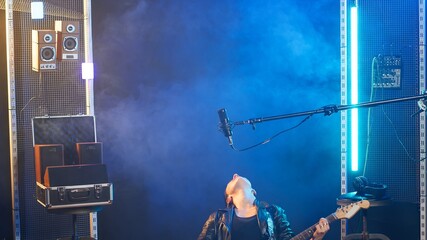 Female recording artist playing bass guitar in a nightclub concert, wearing a leather jacket and...
