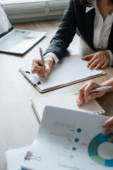 Professionals reviewing financial documents and taking notes during a business meeting in a modern...