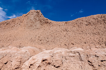 Moon valley famous desert landscape in Chile. Atacama desert tourist sight Valle de la Luna with stunning dry soil arid landscape of red rocks and sand under blue sky  on Altiplano high altitude plain
