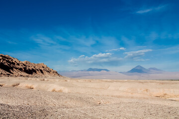 Moon valley famous desert landscape in Chile. Atacama desert tourist sight Valle de la Luna with stunning dry soil arid landscape of red rocks and sand under blue sky  on Altiplano high altitude plain