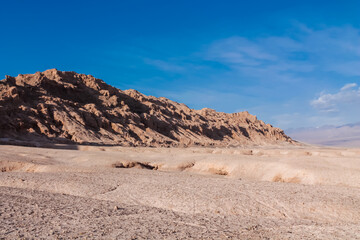 Moon valley famous desert landscape in Chile. Atacama desert tourist sight Valle de la Luna with stunning dry soil arid landscape of red rocks and sand under blue sky  on Altiplano high altitude plain