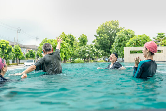 people enjoys a fun water activity in a swimming pool, playing a ball game with smiles and laughter. The scene emphasizes health, active living, and social engagement in an outdoor environment.