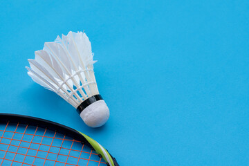 Badminton sport equipments, racket and white cream shuttlecock feather ball on blue floor, soft and...