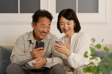 夜のリビングでスマホを使う熟年夫婦