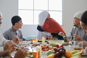 Mother And Daughter Embracing Each Other During Eid Celebration With Family At Dining Room