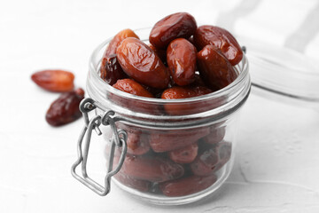 Tasty dried dates in jar on white table, closeup