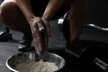 Woman applying talcum powder onto her hands above bowl before training in gym, closeup