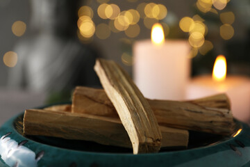 Palo santo sticks and burning candles on table, closeup